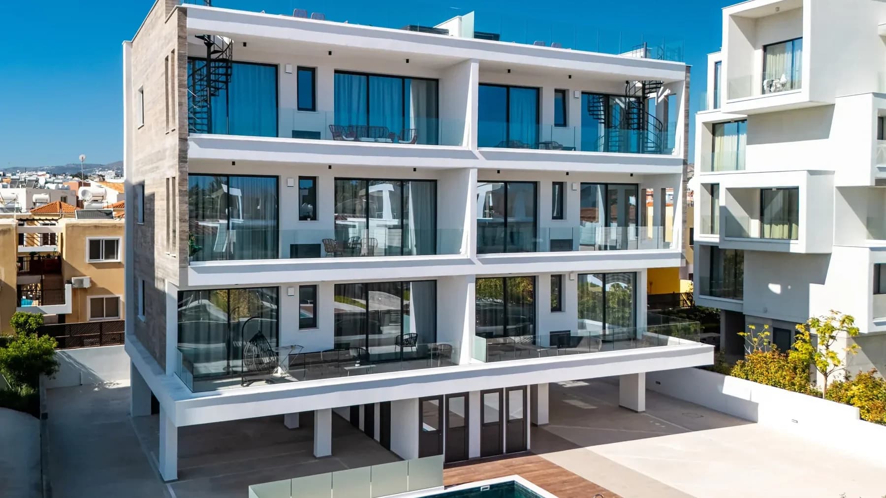 Universal Park 1 from above: a white apartment building with balconies and a pool with timber decking below